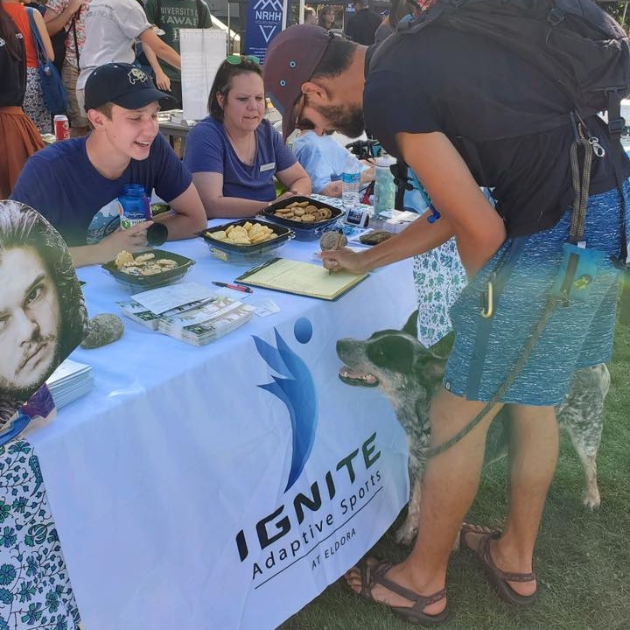 a man signing an Ignite volunteer interest form at a local farmers market event