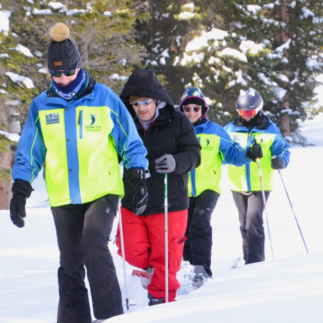 Ignite Athlete enjoying adaptive snow shoeing with three Ignite Volunteer Instructors