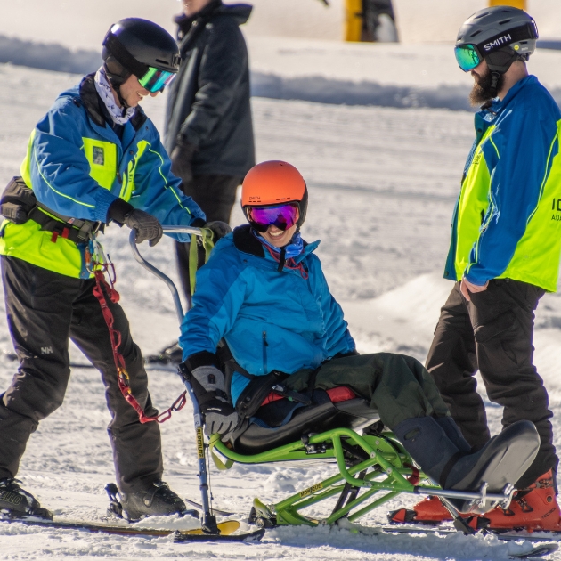 Ignite Athlete getting ready with two Ignite Volunteer Instructors on a sit ski to go on a run at Eldora Mountain Resort