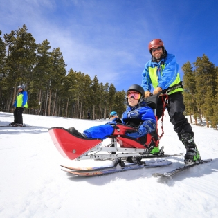 Oasis Pediatric Therapy client on a sit ski with Ignite Volunteer Instructor