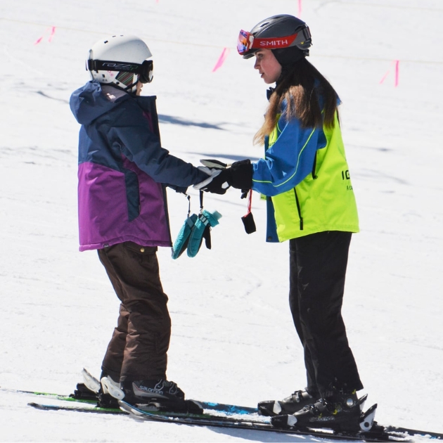 Ignite Junior Instructor holding the hands of an Ignite Athlete as they go down a ski run together