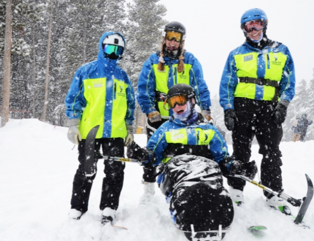 on a heavy snow day, a team of Ignite Volunteers Instructors smile on the top of a run