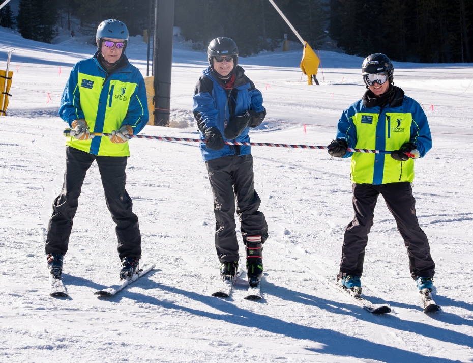 Ignite Athlete using adaptive equipment for balance that is supported by two Ignite volunteer instructors on both ends