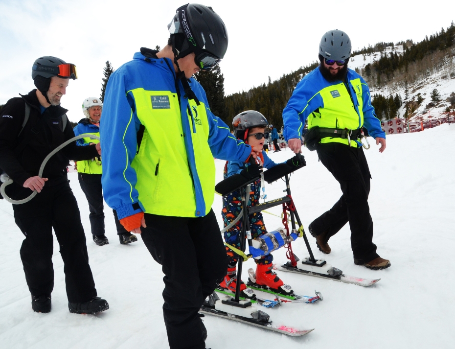 Ignite Athlete using adaptive ski equipment being guided by Ignite volunteer instructors