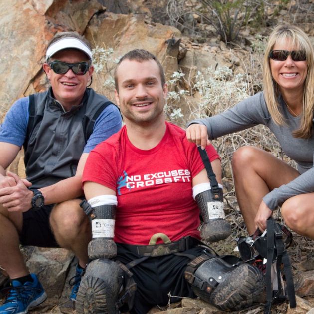 Smiling man with prosthetic limbs hiking alongside two friends.