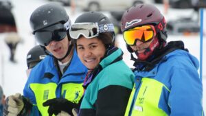 An Ignite athlete with two Ignite volunteer instructors pose together on a snowy slope