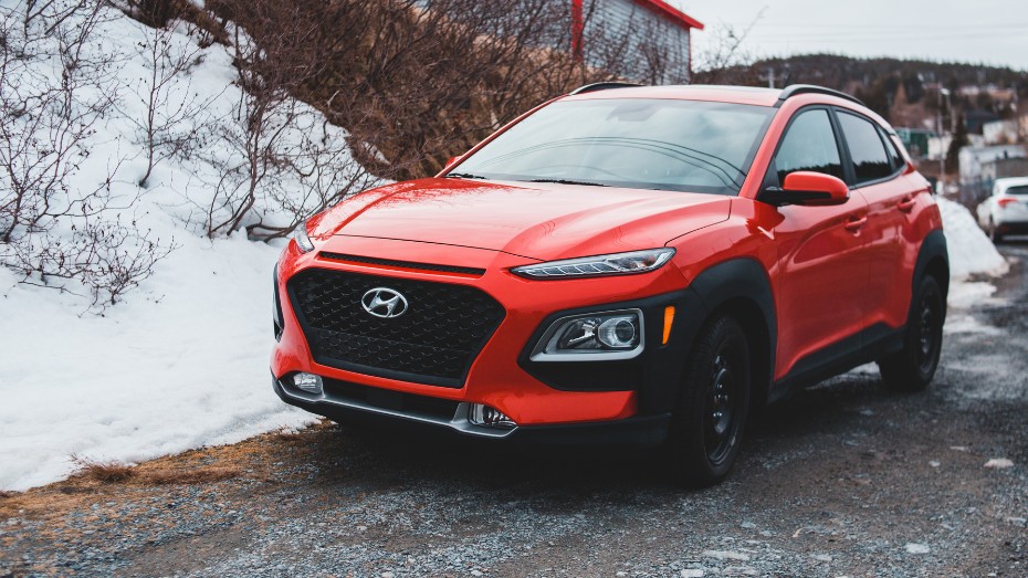 A red car parked on the side of the road on a snowy day